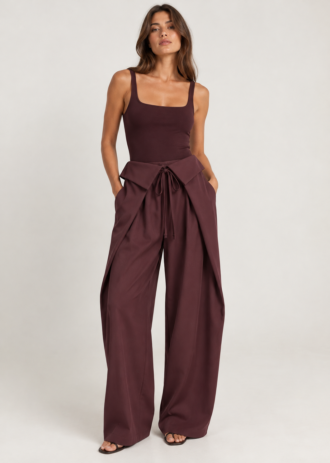 Model wearing burgundy draped wrap-front wide-leg trousers with a matching fitted tank top