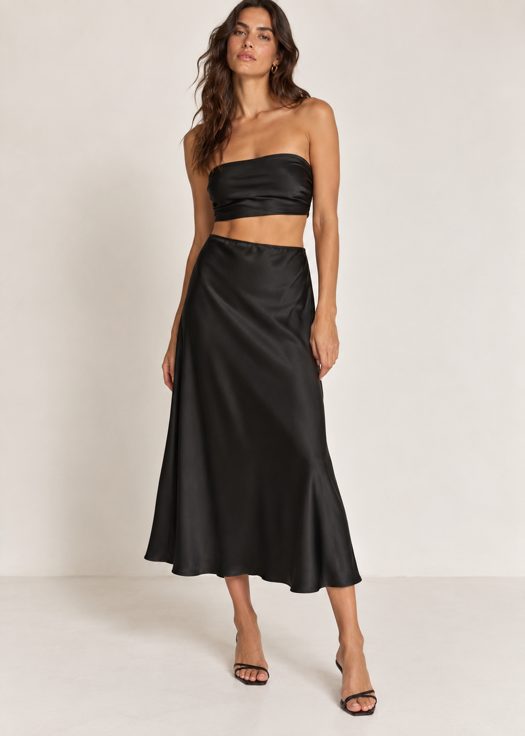 Black satin-look midi skirt shown from the front against a white background
