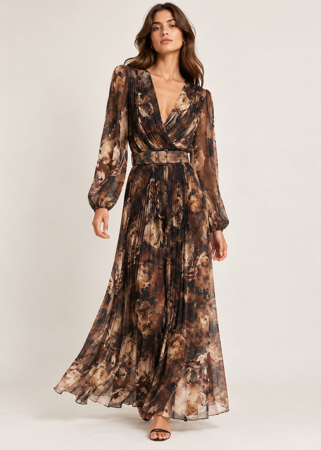 Model wearing a flowing floral pleated maxi dress with sheer long sleeves