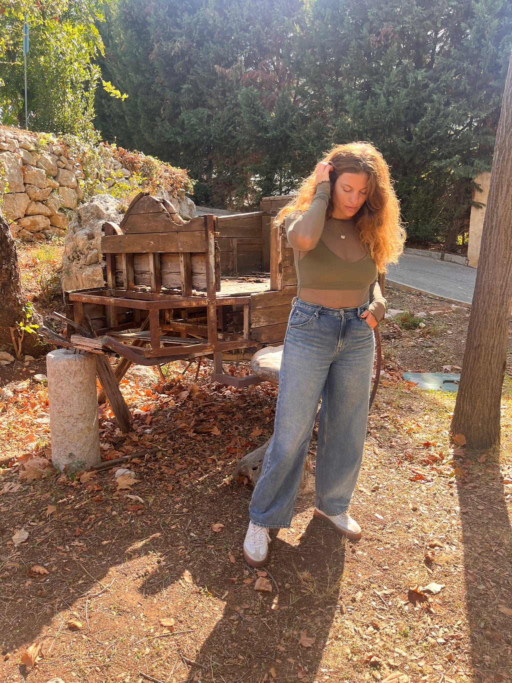 Person standing outdoors with a wooden structure and trees in the background