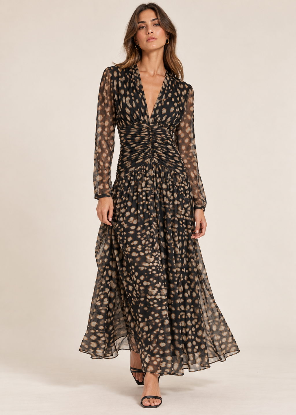 Model wearing black and beige spotted ruched maxi dress with sheer sleeves and black heels